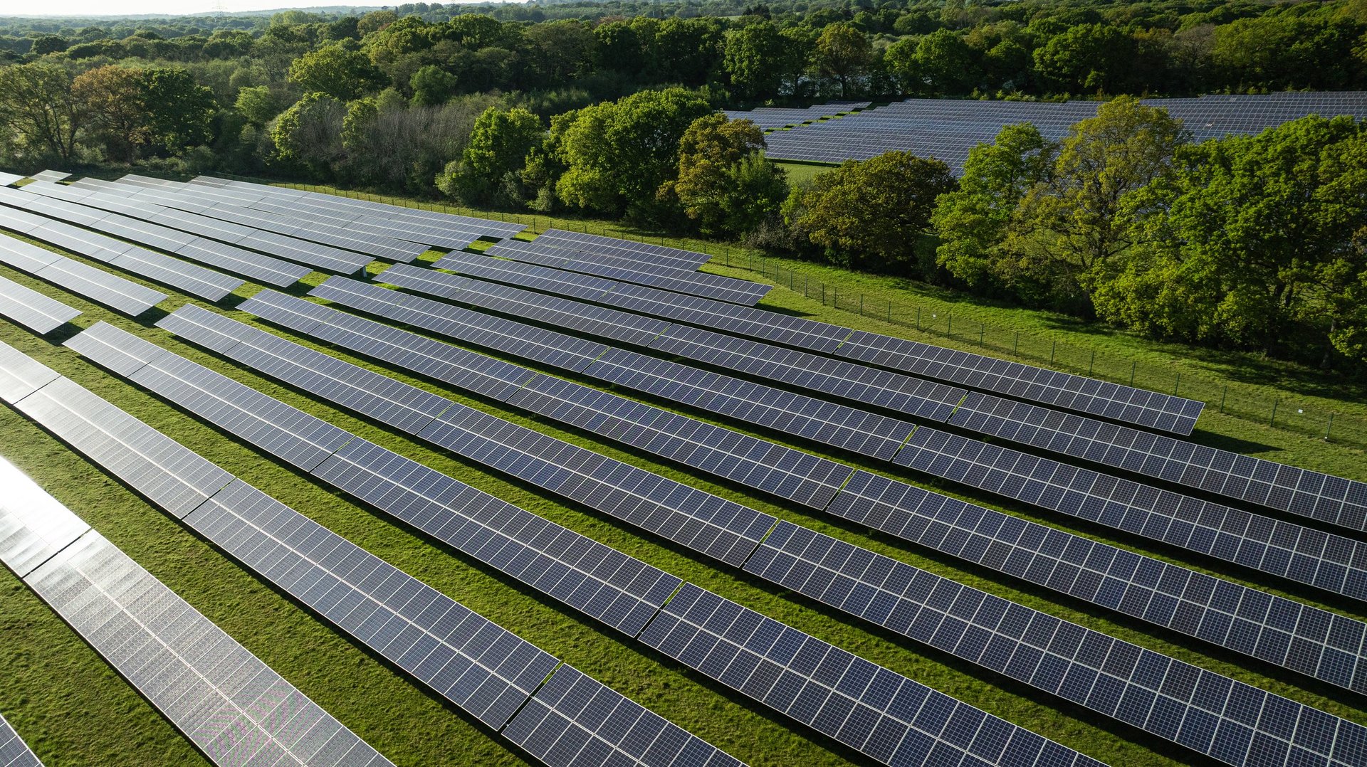 Aerial view of a solar installation in a green landscape beside a lake